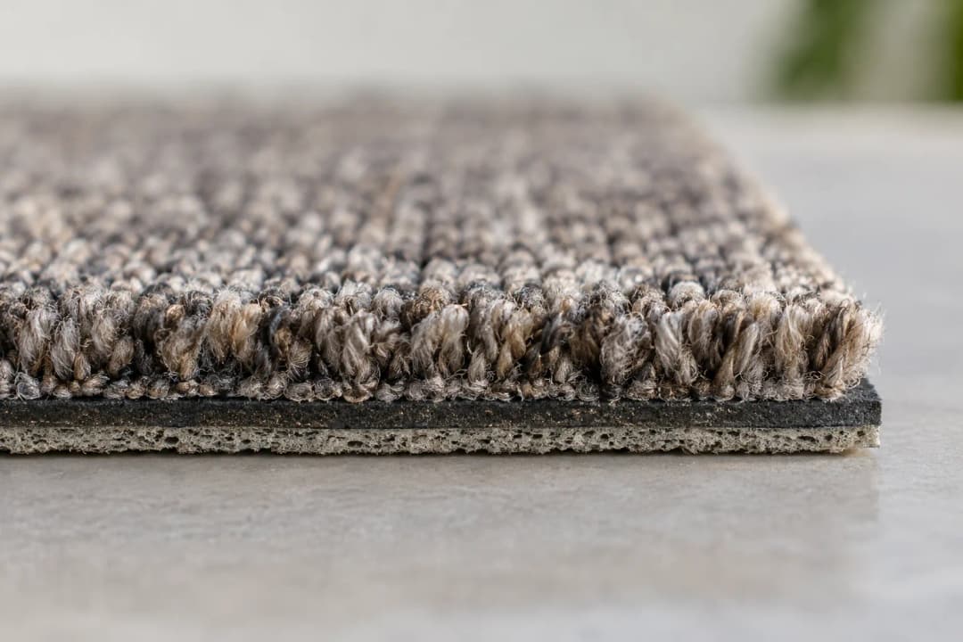 Cut edge of a carpet tile showing textile face and backing layers