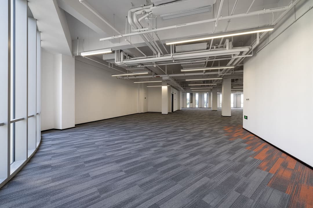 UNIJOY carpet tile floor with visible module direction in an open commercial interior, used as visual context for pattern-matching decisions