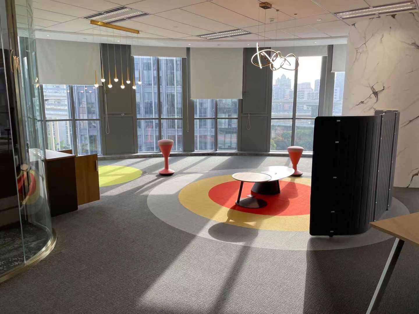 UNIJOY carpet tile in a bright office lounge with a circular multi-colour layout, used as visual context for reviewing module direction and light